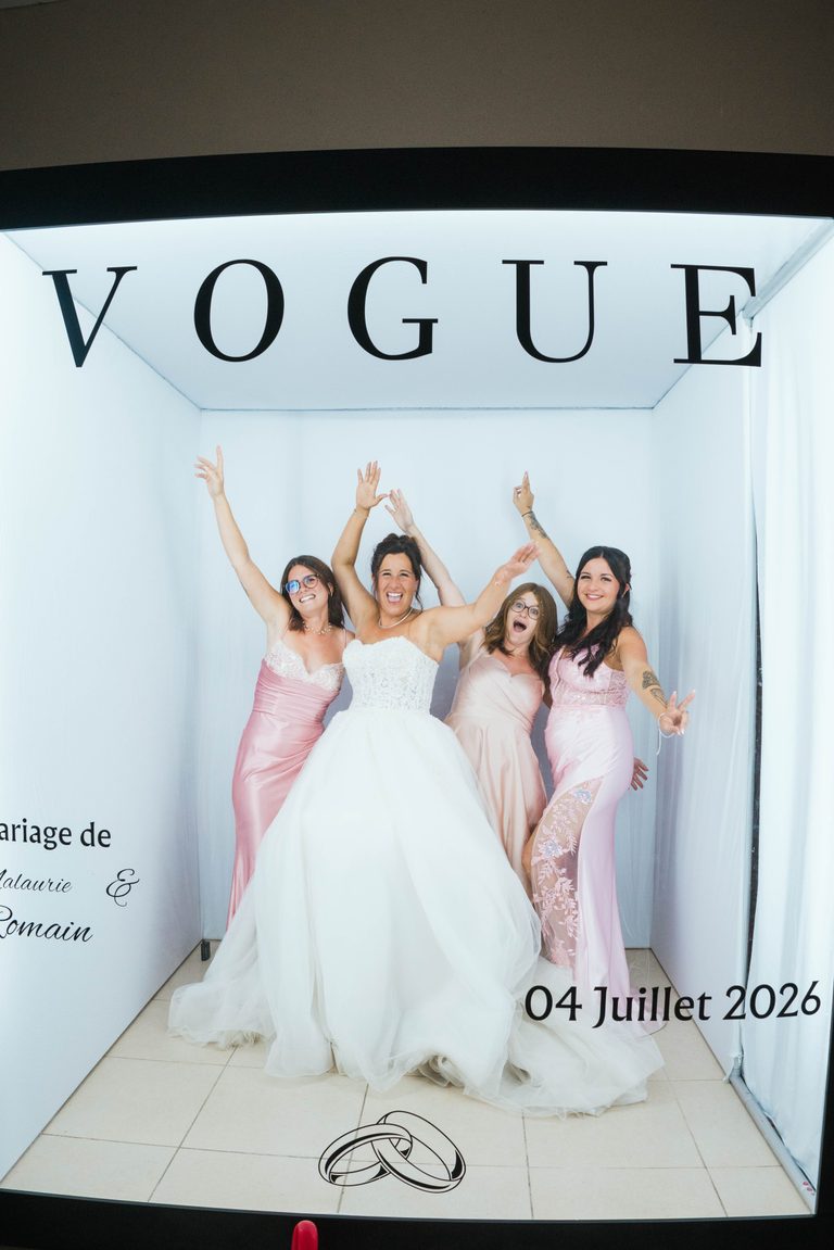 La Magazine Box en mariage : la mariée et ses demoiselles d'honneur bras levés dans le cube lumineux façon couverture de VOGUE personnalisée